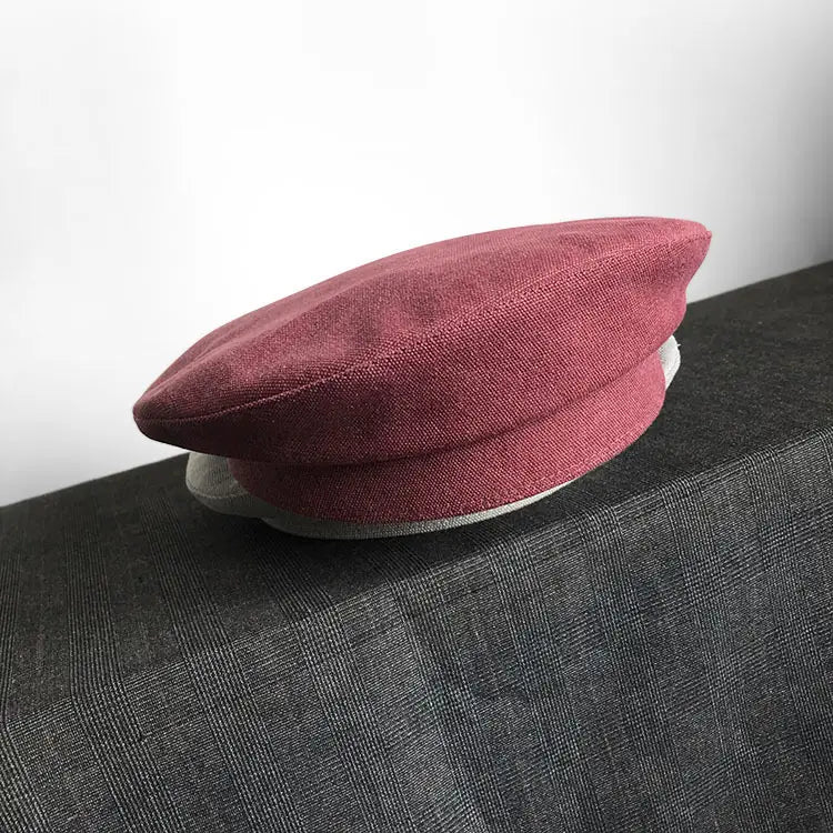 Béret en laine bordeaux texturé, souple, avec un motif tissé discret et une doublure intérieure blanche impeccable, conçu comme un béret noir en laine pour peintre pour femmes.