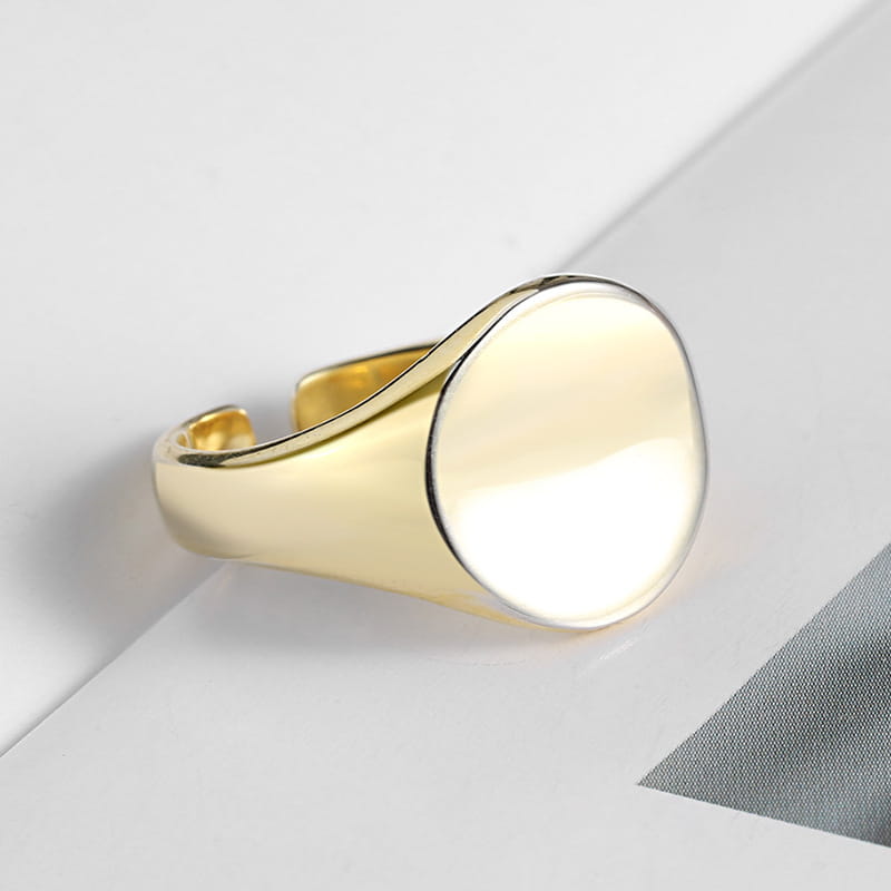 Gold-toned adjustable oval minimalist signet ring with a smooth polished face and metal band.