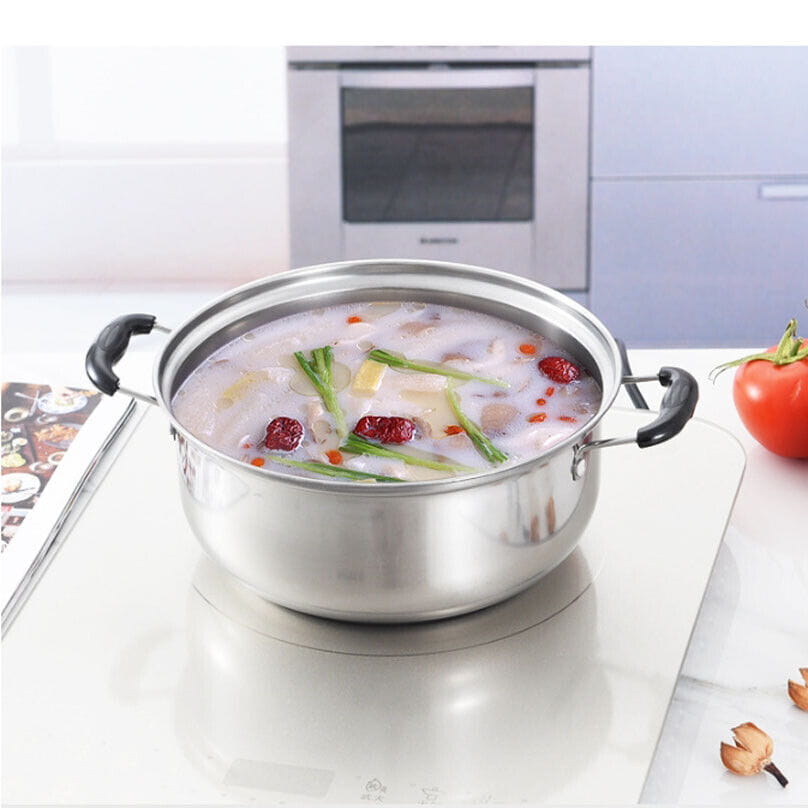 Stainless steel induction cookware set 5 pieces featuring a stainless steel pot with black handles filled with creamy vegetable soup and red dates.