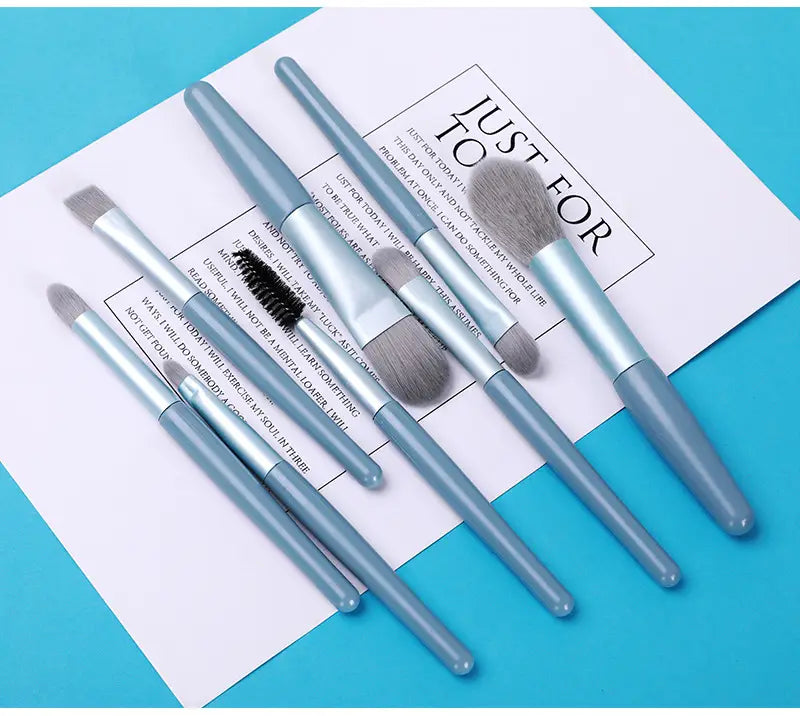 Set of seven light blue plastic-handled makeup brushes with soft gray bristles included in an 8-piece makeup brush set with leather case.