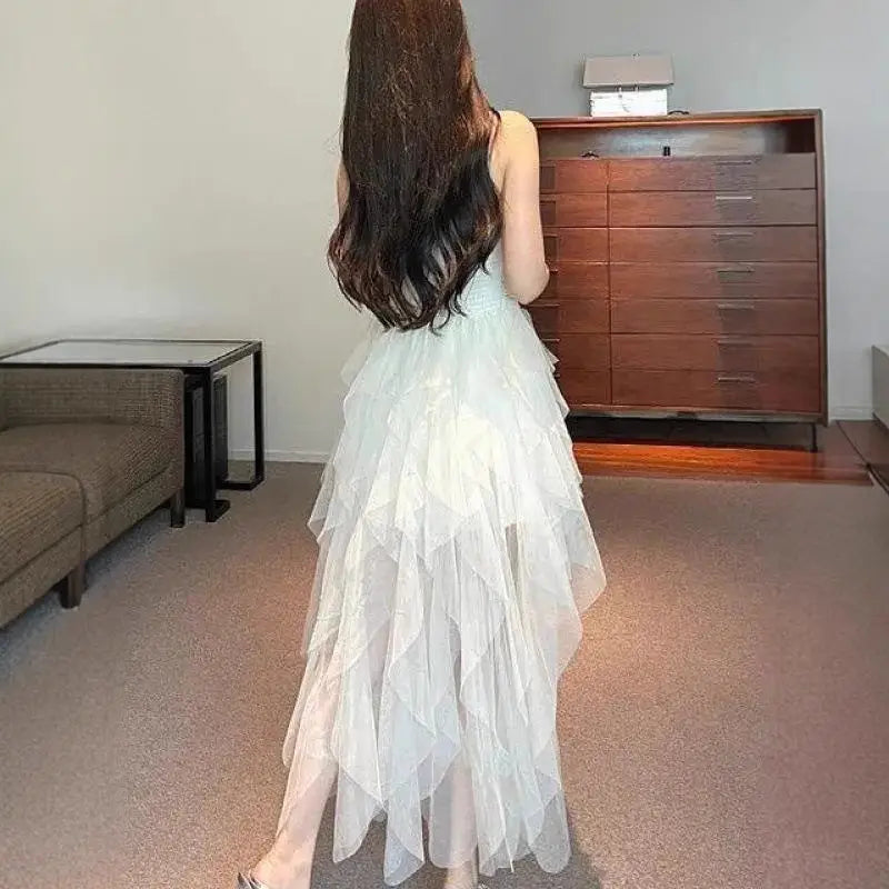A flowing off-white tiered tulle and lace mesh evening gown with delicate spaghetti straps.