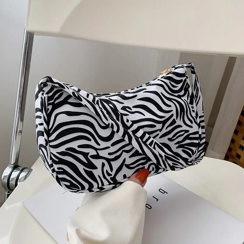 A black and white zebra-print underarm shoulder bag for women featuring a sleek curved design.