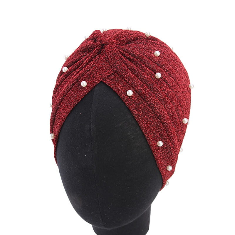 A shimmering red pearl turban headscarf cap for women made of jacquard fabric adorned with evenly spaced white pearls along its twisted design.
