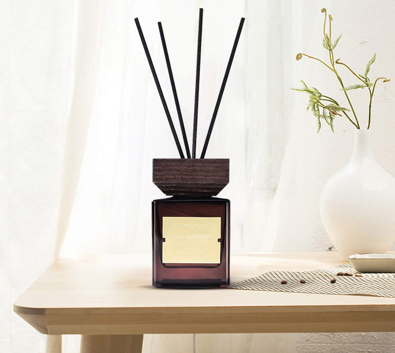 Caractéristiques du diffuseur à roseaux en verre noir pour parfum d’hôtel : dessus en bois foncé et verre ambré, avec des roseaux noirs et une étiquette dorée.