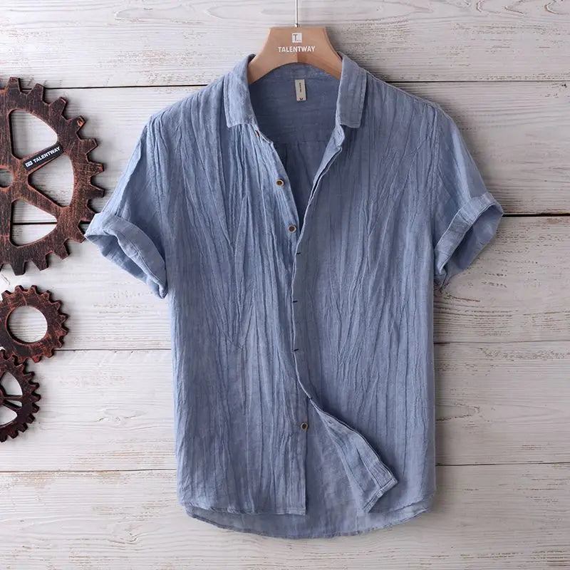 Men’s retro distressed linen short sleeve shirt in light blue textured cotton with rolled cuffs and a collar.