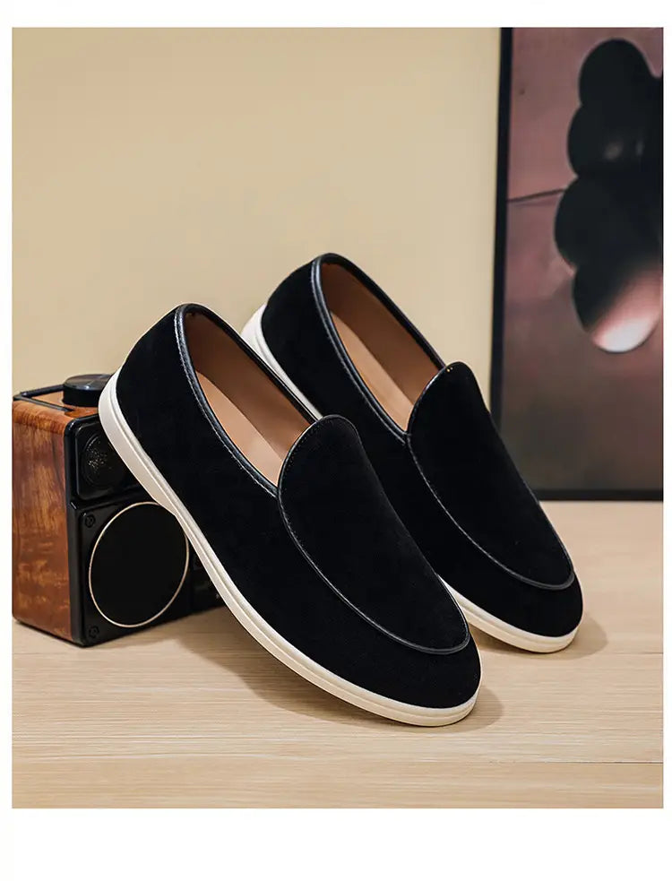 Men’s black suede slip-on loafers with white rubber soles and contrasting stitching for casual wear.