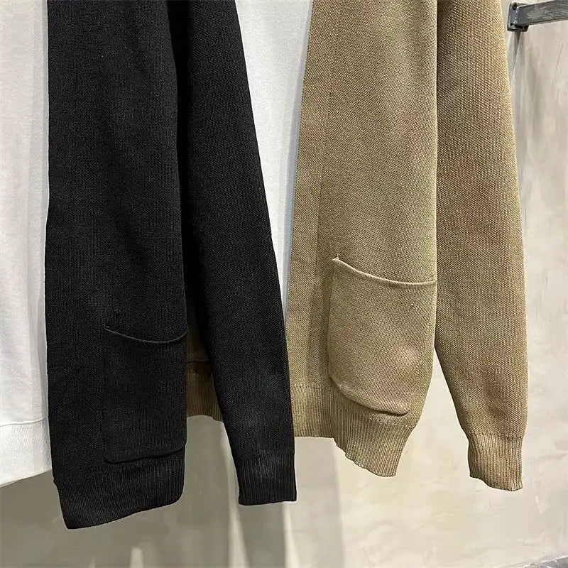 Herren-Strickcardigan in Schwarz und Beige mit gerippten Bündchen und Fronttaschen aus weichem Strickmaterial.