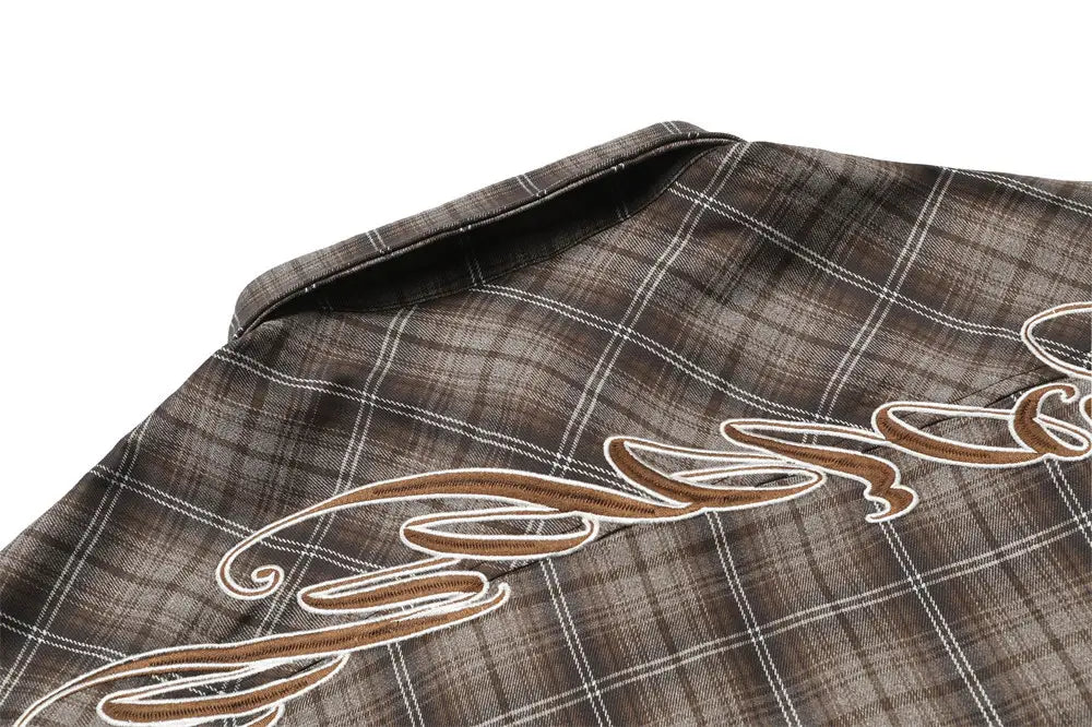 Brown and white plaid short sleeve shirt featuring intricate embroidered script detailing on fabric.