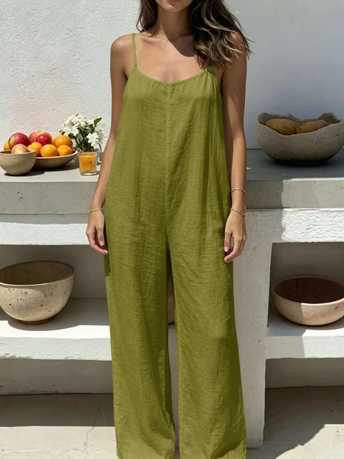 Olive green linen wide leg backless jumpsuit with thin spaghetti straps shown from the back.