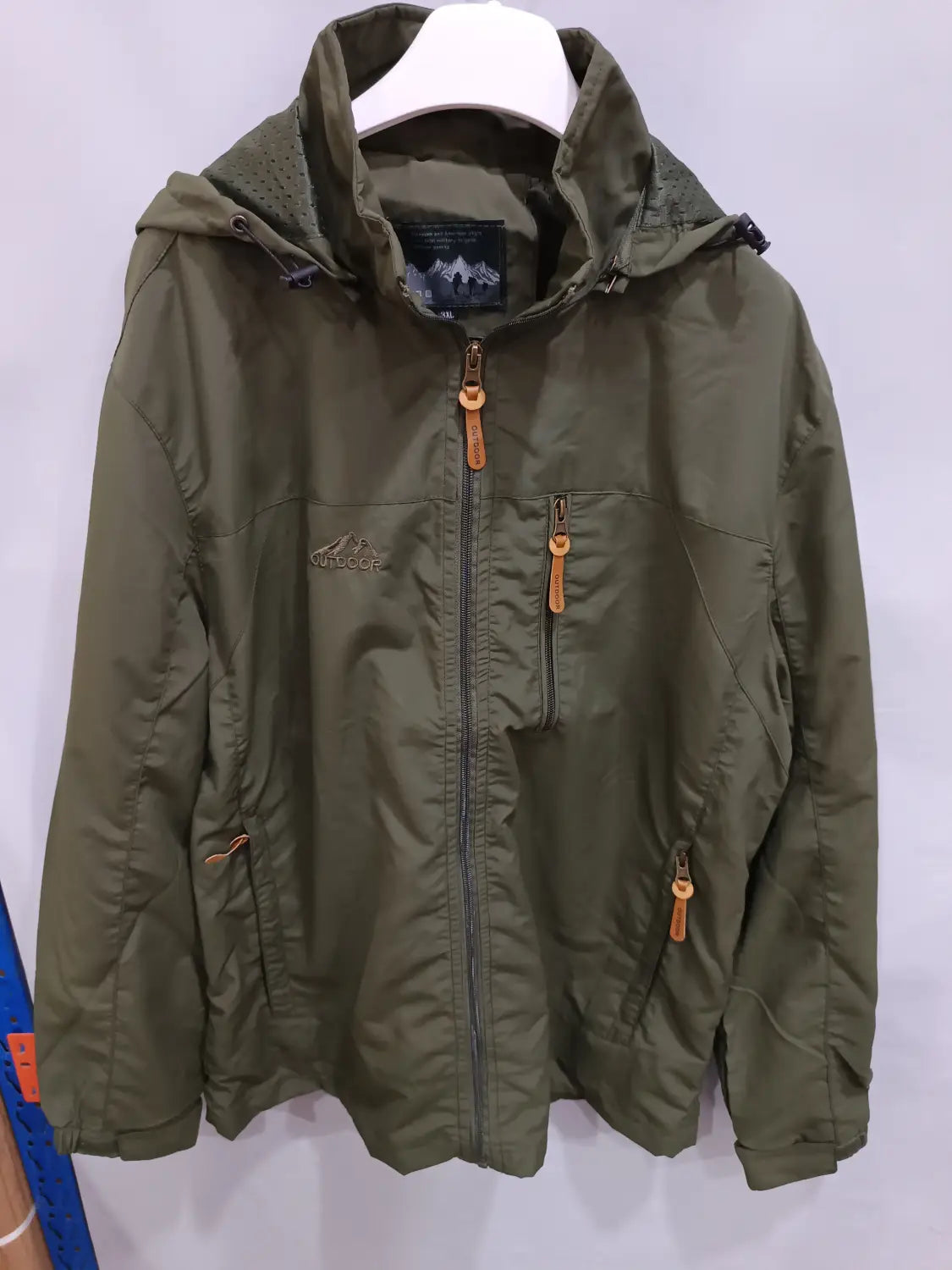 Chaqueta de senderismo con capucha impermeable color verde oliva, con cremallera frontal y bolsillos laterales, con tiradores color cuero.