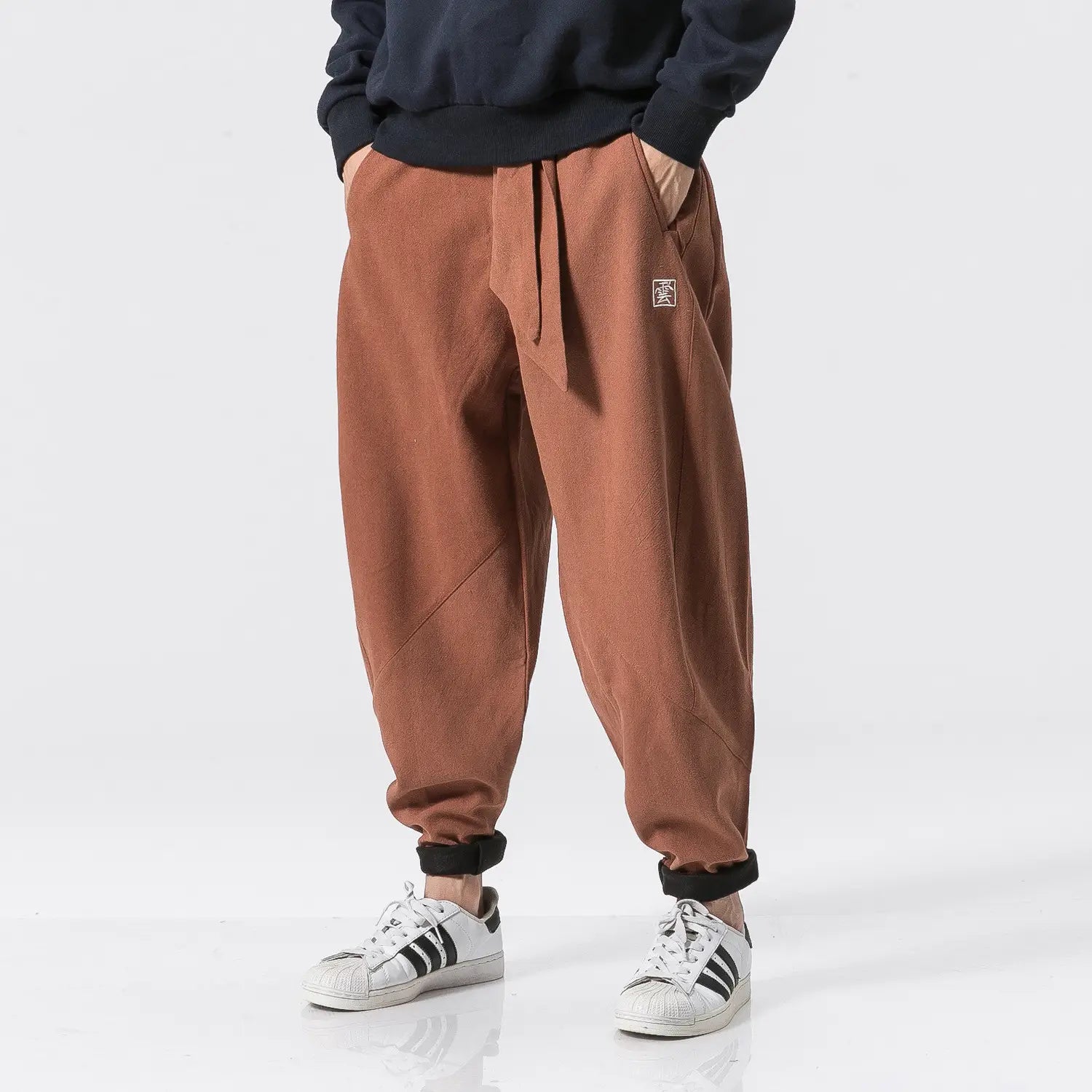 Herren-Veloursfutter-Cargo-Jogger in Braun aus Baumwolle mit Kordelzug in der Taille und schwarzen elastischen Bündchen.