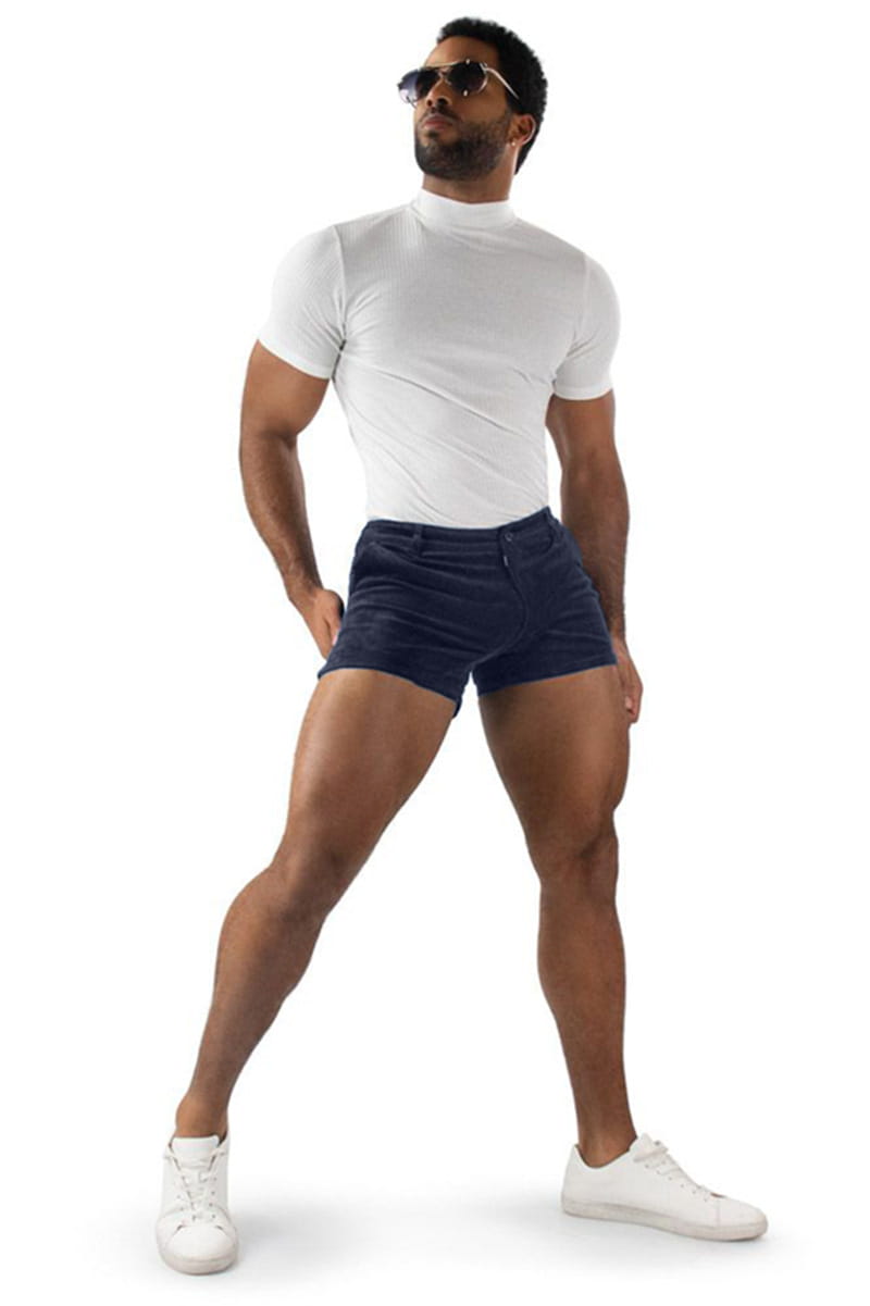 A man wearing navy blue corduroy beach shorts with a mid rise paired with a white short-sleeved turtleneck top.