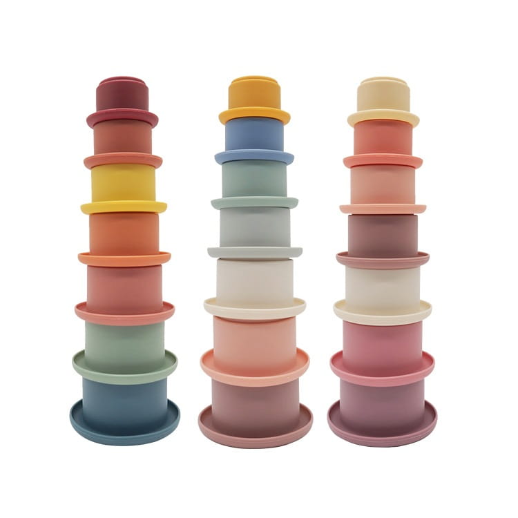 Three stacks of pastel-colored silicone stacking cups with unique gradient patterns and a smooth matte finish designed as an educational nesting baby toy.