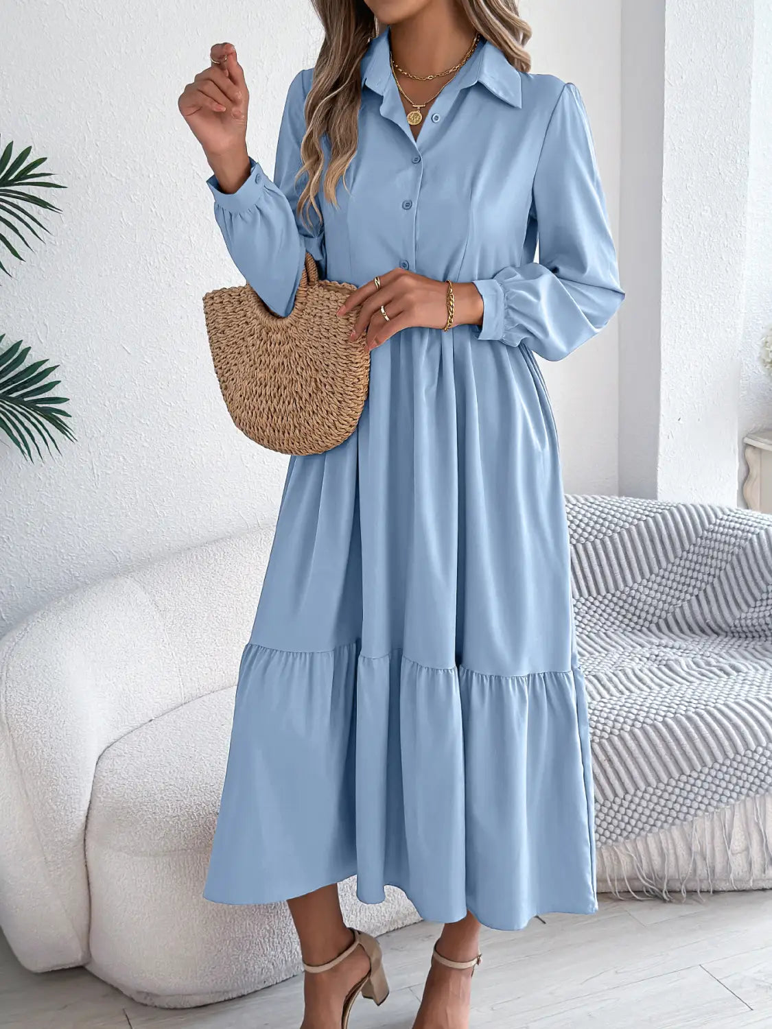 A light blue women’s long sleeve tiered button down midi dress with a collar and a flowy skirt.