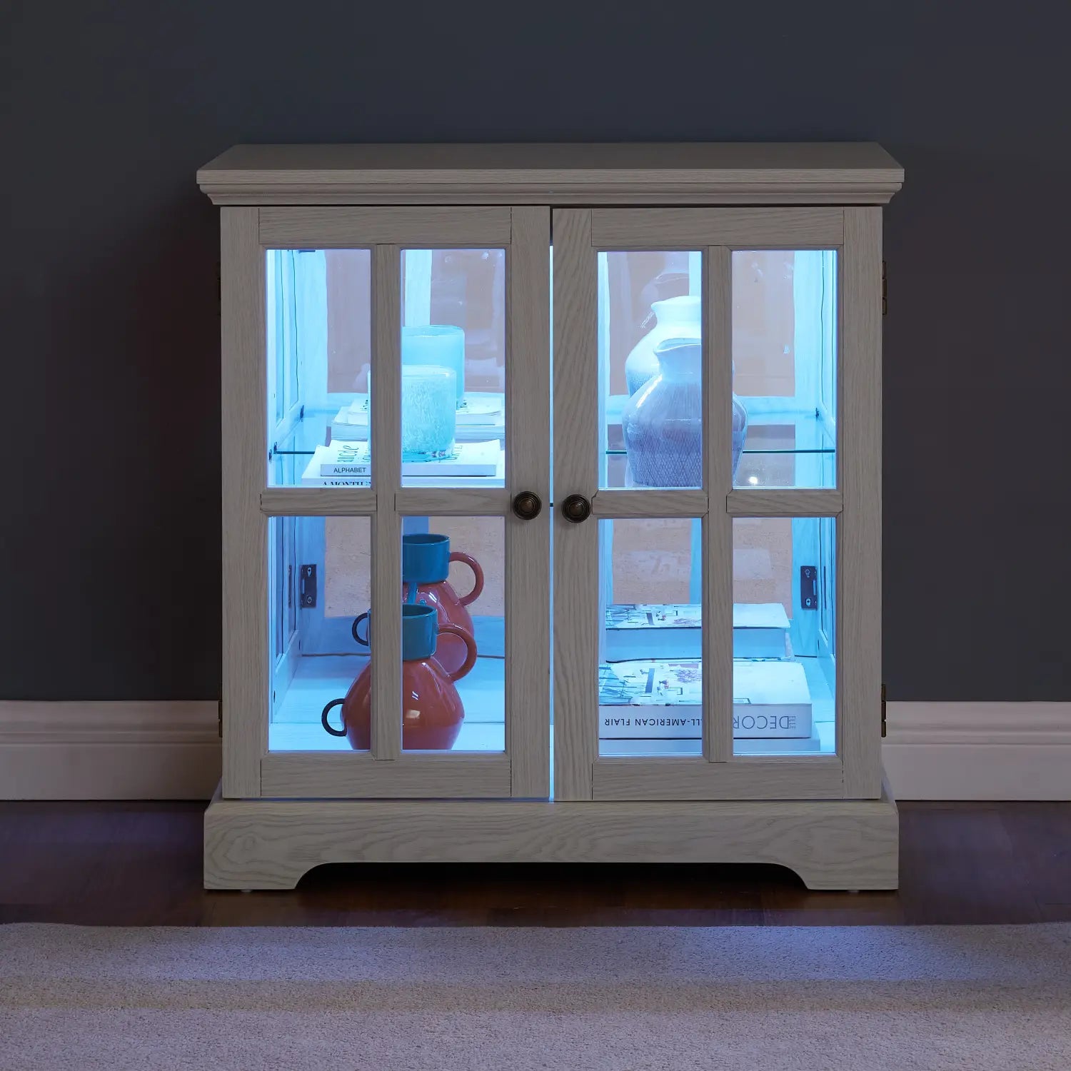 Led curio display cabinet featuring a lighted white wooden structure with glass lattice doors and black handles.