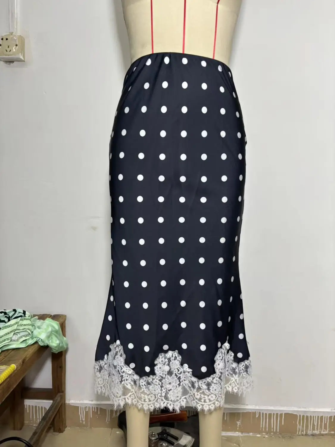 Jupe midi en satin bleu marine avec pois blancs et une délicate bordure en dentelle le long de l’ourlet.