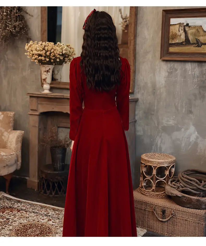 A rich crimson velvet long sleeve a-line gown with a high neckline and flowing silhouette.