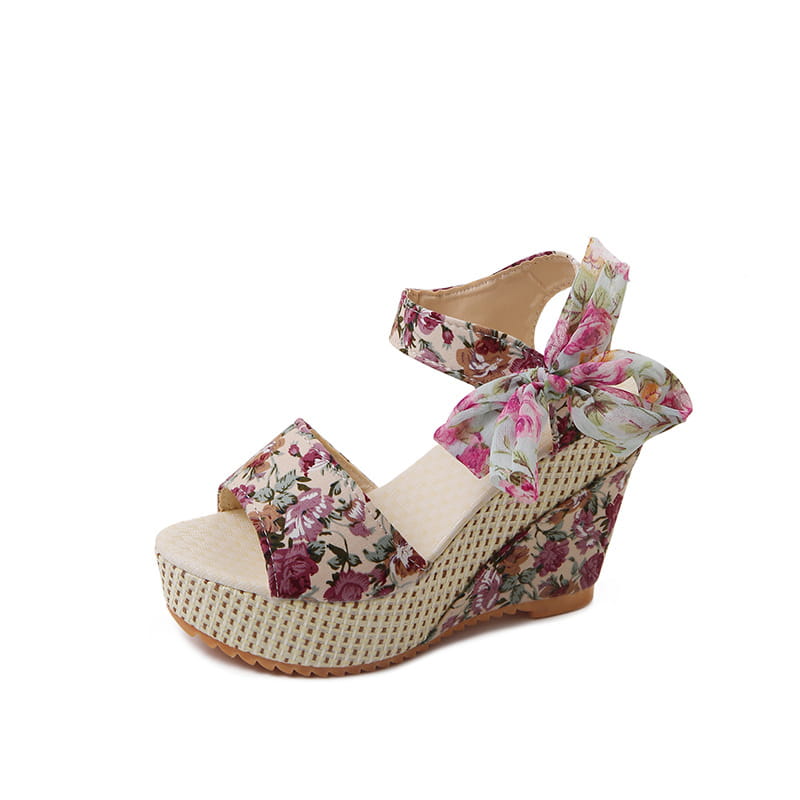 Floral bohemian platform wedge sandal featuring a woven beige sole and fabric straps with a pink rose floral pattern and ankle ties.
