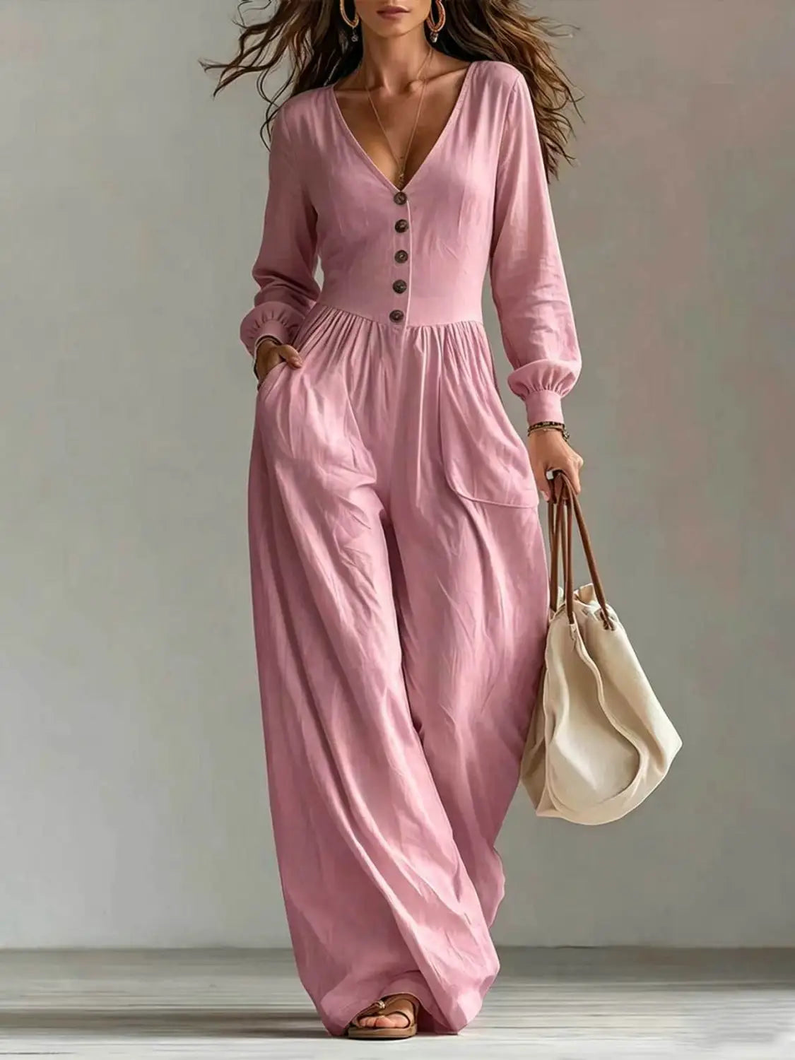 Une combinaison longue ample à manches longues en V pour femmes, rose tendre, à jambes larges, avec fermeture boutonnée et une coupe confortable.