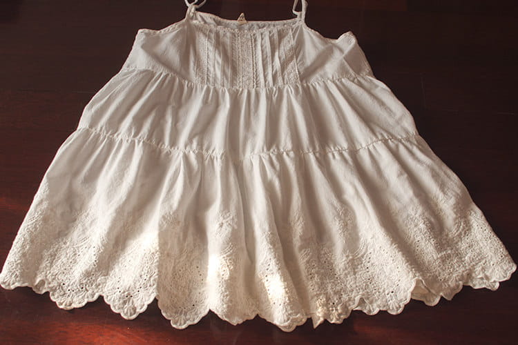 Ein weißes Spitzenkleid mit Volants (gestufter Rock) mit zarten Lagen, Spitzenbesatz und dünnen Spaghettiträgern.