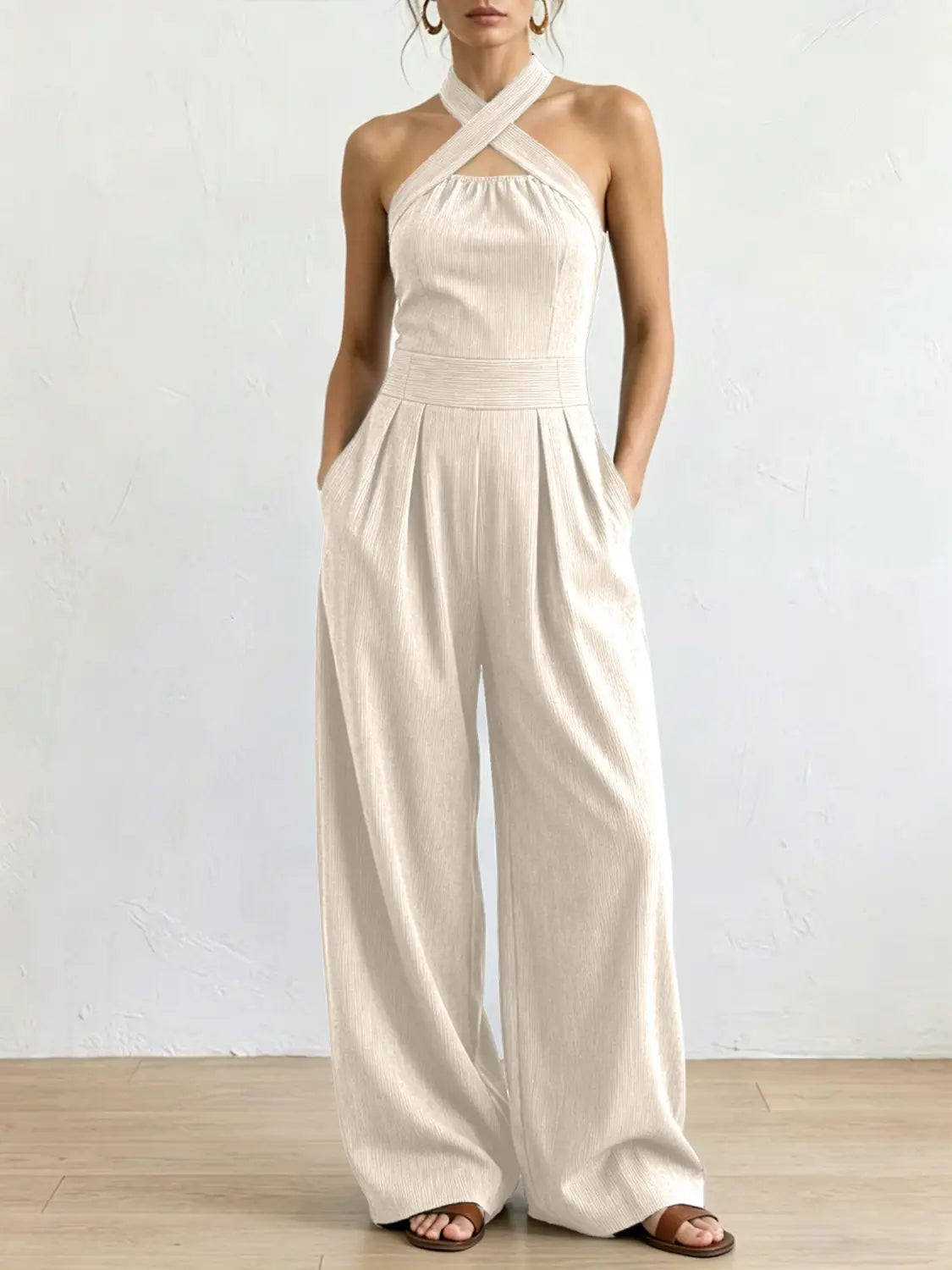 Ein fließender Jumpsuit aus elfenbeinfarbenem, geripptem Stoff mit Halterneck, mit Halterneck-Ausschnitt und Hosen im weitem Bein.
