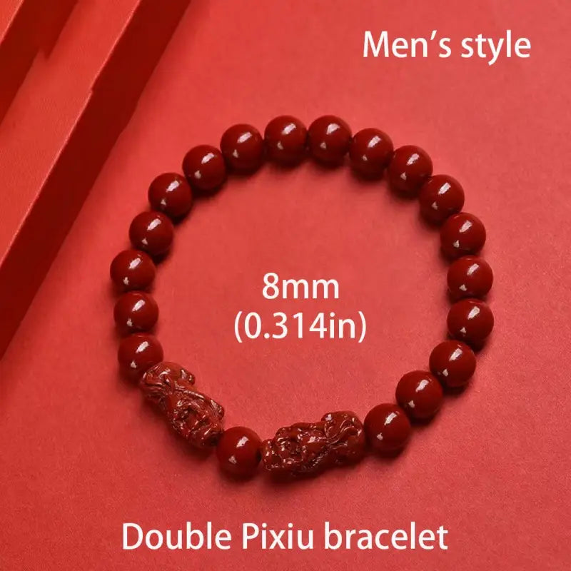 Red 8mm round bead bracelet made of purple gold cinnabar featuring two hand carved pixiu figurines as decorative accents.