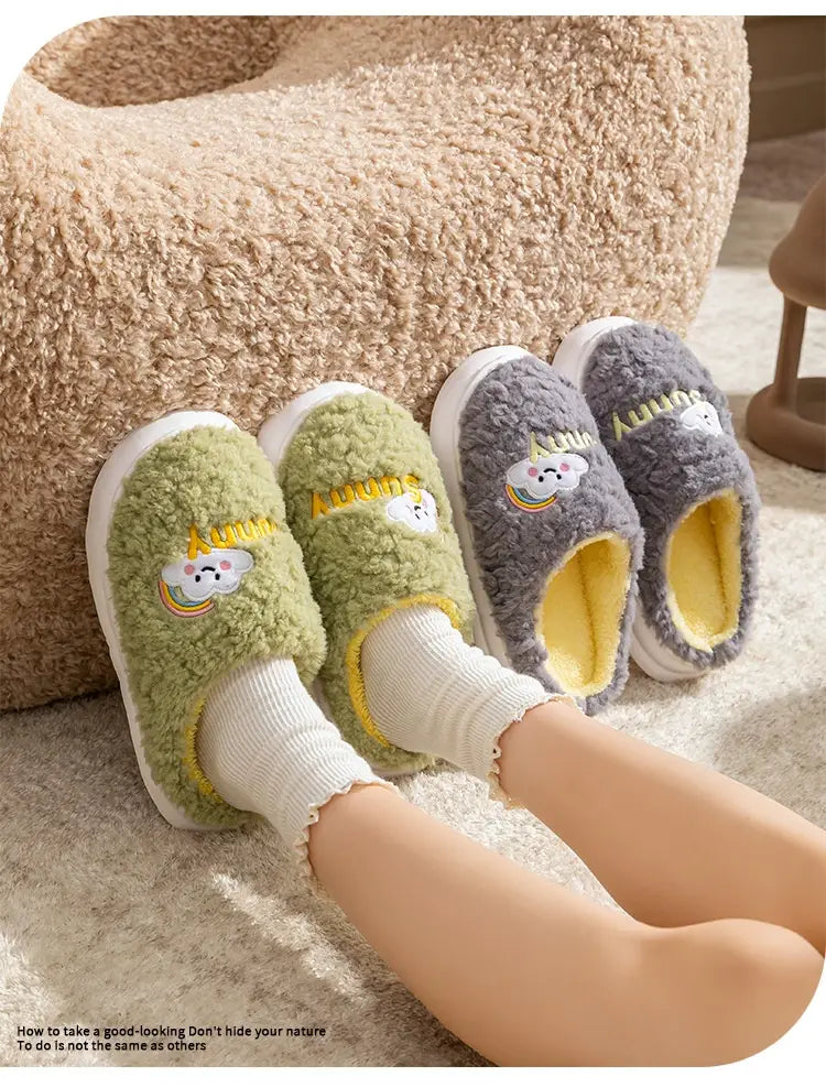 Soft fuzzy green and gray cotton slip-on slippers with embroidered smiling cloud and rainbow designs on the front.
