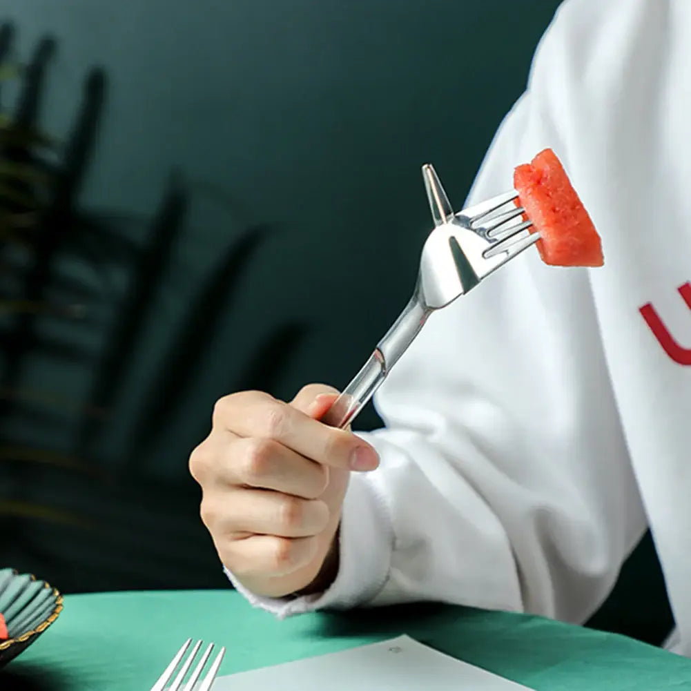 une élégante fourchette-slicer à pastèque en acier inoxydable au design moderne maintient une tranche de pastèque rouge comme coupeur et fourchette 2-en-1.