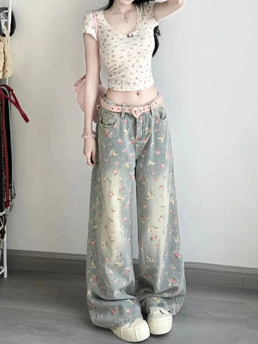 Floral high waist wide leg denim jeans in soft sage green featuring a floral pattern with delicate pink and yellow blossoms and a heart-shaped belt buckle.