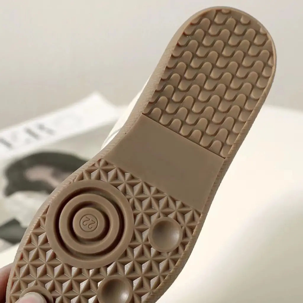 Beige Gummisohle mit strukturiertem Muster und kreisförmigem Laufsohlenprofil von Ledersneakern, vielseitige Freizeitschuhe im Low-Top-Design.