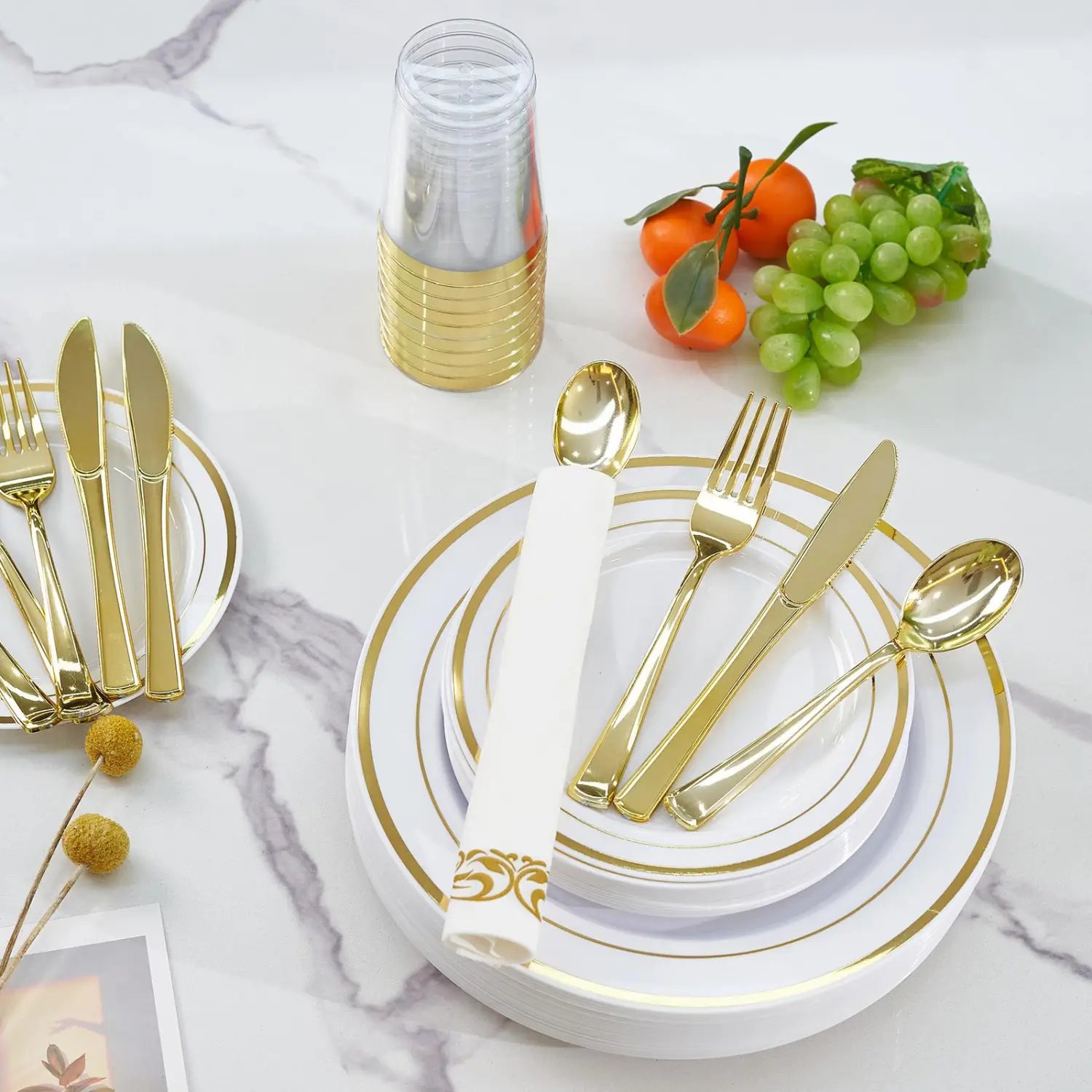 Plastic tableware set with gold-plated plastic cutlery and matching white plates with gold rims and decorative patterns for 50 guests.