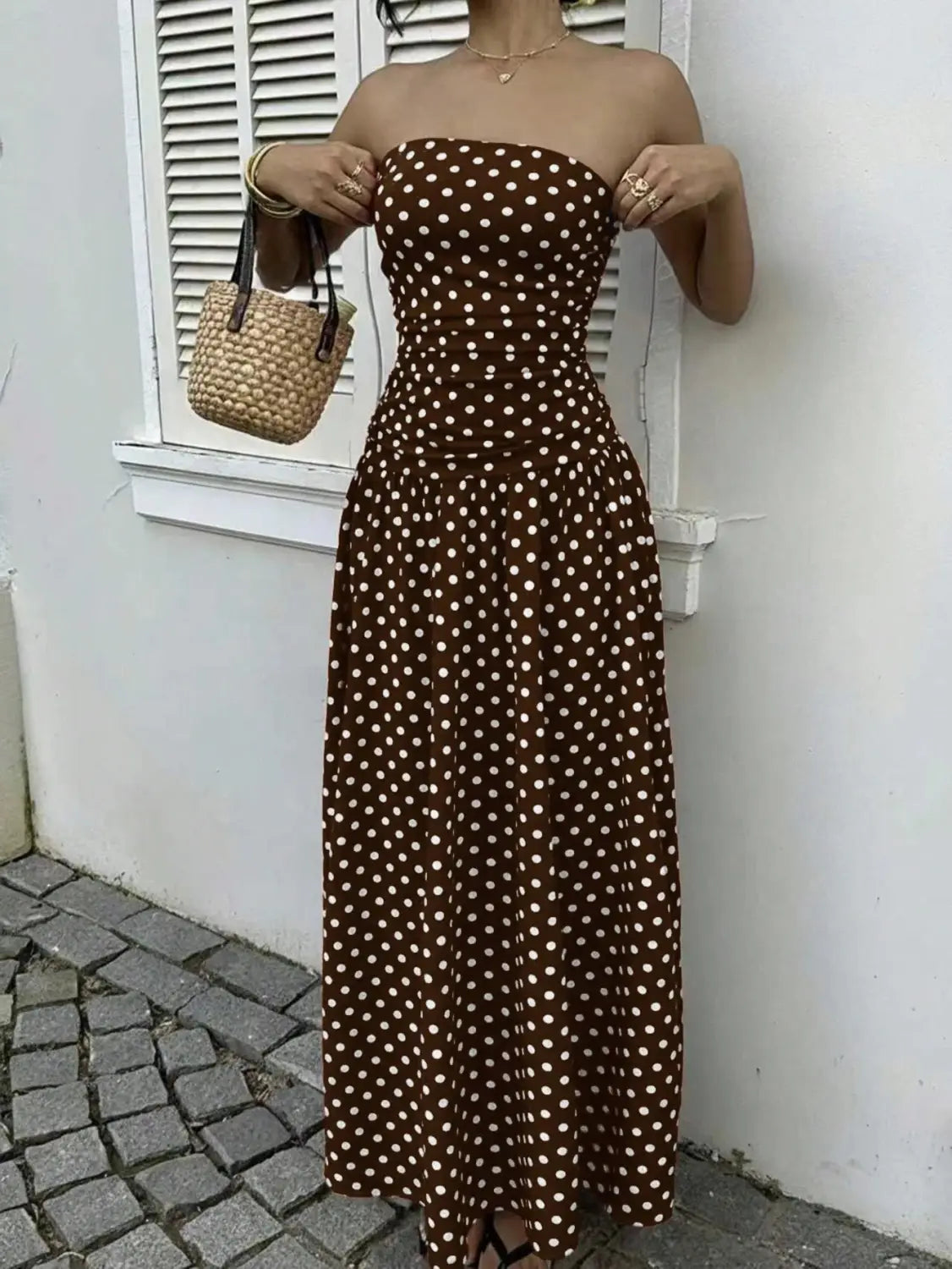 A brown strapless maxi dress with white polka dots featuring an off shoulder design.