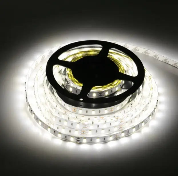 Coiled white waterproof led strip light on a black spool emitting bright illumination for flexible home decor use 5m.