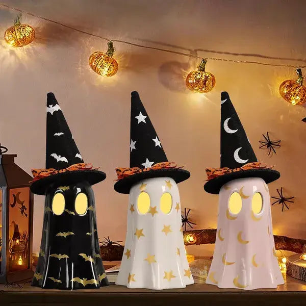 Tres faroles de Halloween de cerámica con aspecto de fantasmas, ojos amarillos brillantes y sombreros de bruja decorados con estrellas, lunas y murciélagos.