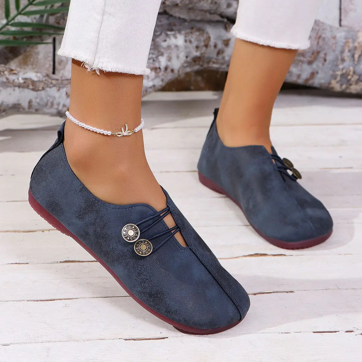 Navy blue suede women’s square toe lace-up leather and suede loafers with decorative brass buttons and a contrasting red sole.