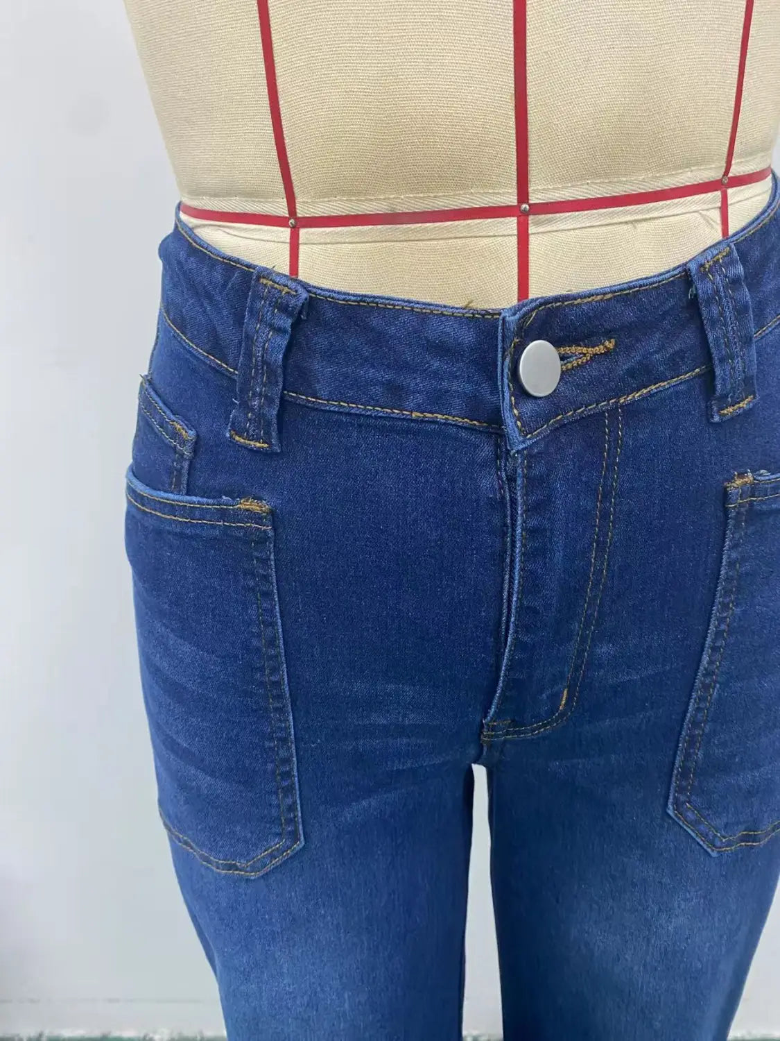 Wide leg dark blue denim pants with button closure front pockets and attached belt made of denim material.