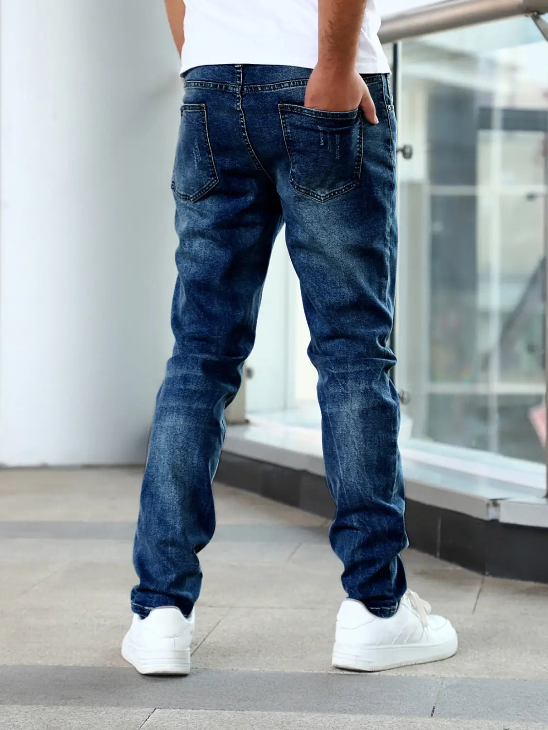 men’s slim fit distressed dark wash denim jeans shown from the back side featuring dark blue denim with subtle fading and classic back pockets