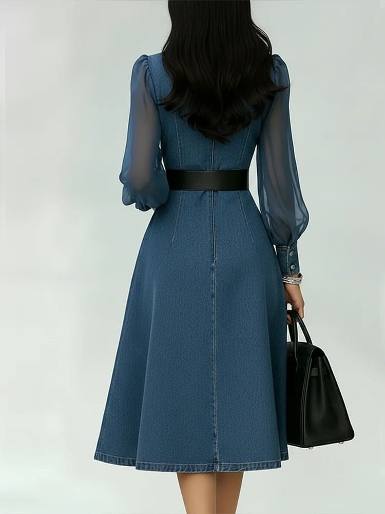 Ein blaues Midikleid aus Denim mit transparenten langen Ärmeln und einem schwarzen Gürtel, das ein Color-Blocking-Design zeigt.