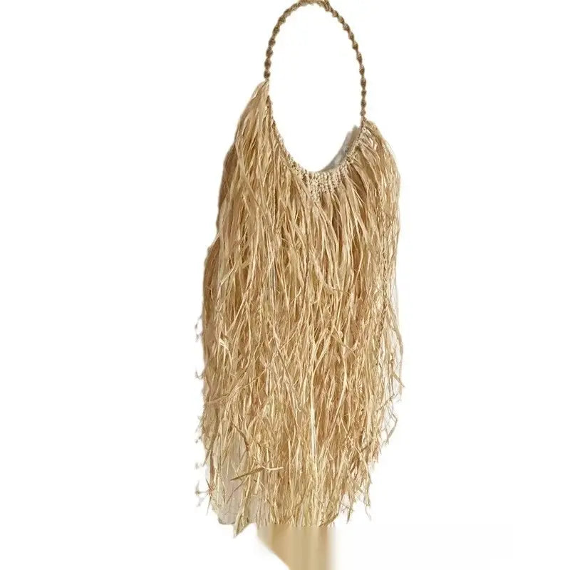 Un bolso de paja color beige con flecos, asa superior trenzada y cuentas decorativas, presentado junto con un adorno de pared de rafia estilo boho de tapiz colgante de macramé.