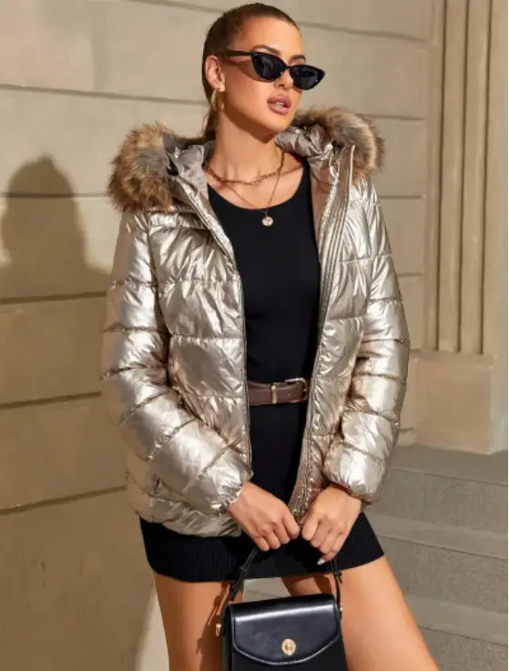 A women’s hooded puffer jacket in shiny metallic silver with a fur-lined hood and quilted insulation.