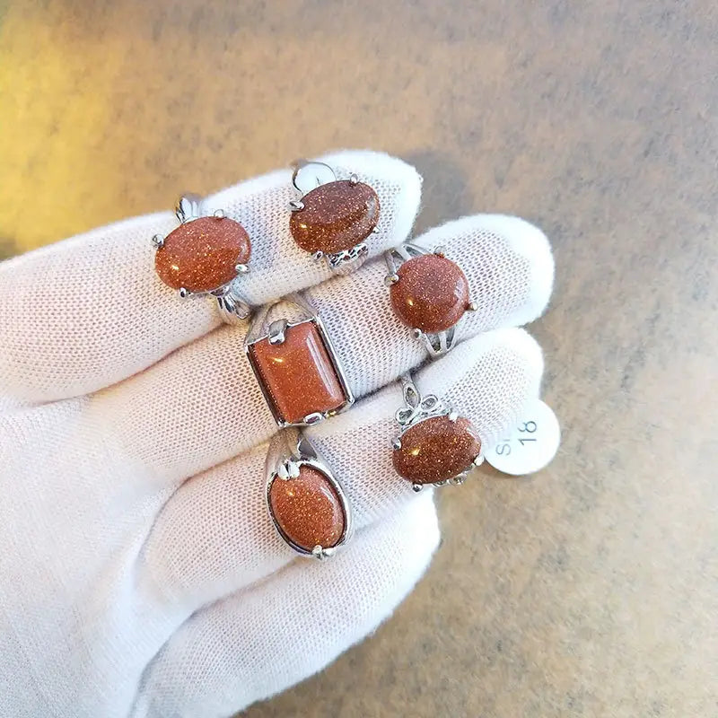 A set of five natural gemstone silver tone statement rings featuring oval and rectangular orange gold sandstone gemstones.