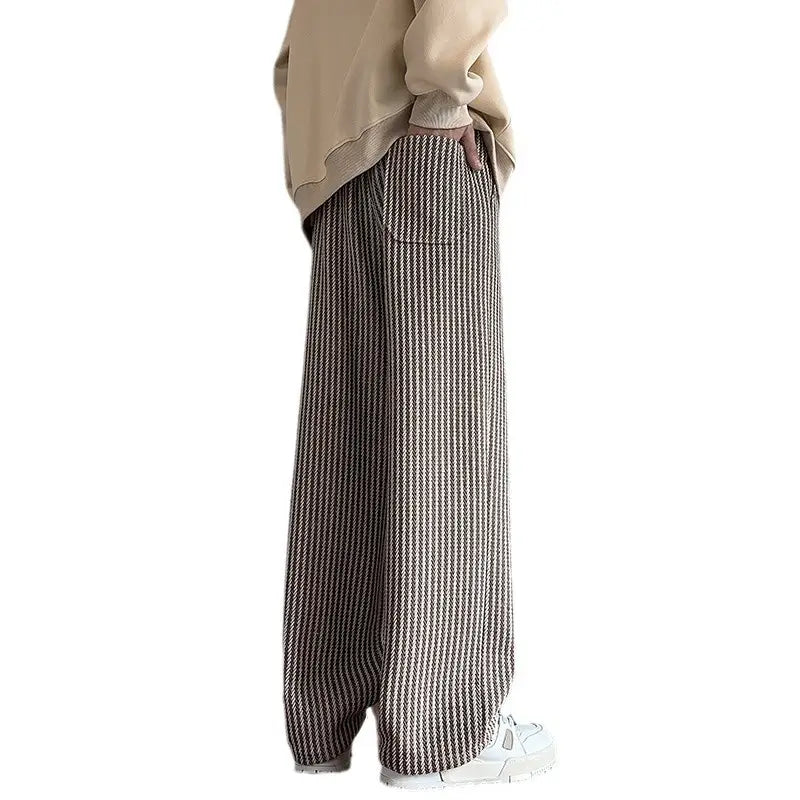 Men wide leg herringbone drawstring trousers with a textured vertically striped pattern in earthy tones of beige and dark brown.