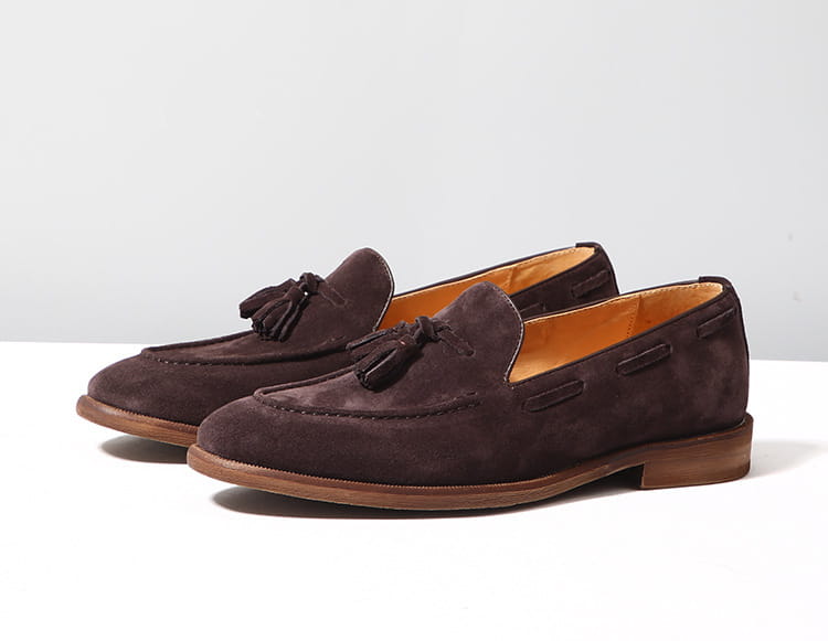 Mocassins à pampilles en daim beige, présentant un matériau en daim marron, des pampilles noires et une doublure intérieure beige, avec une semelle en caoutchouc cousue.