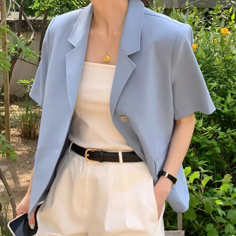 Un blazer pour femmes bleu clair à manches courtes avec un col structuré et une fermeture à un seul bouton, conçu comme une veste décontractée à coupe décontractée.