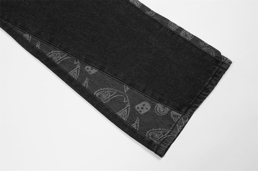 Men’s distressed paisley patchwork flare jeans in black denim featuring a subtle gray paisley and skull pattern along the inner seam.