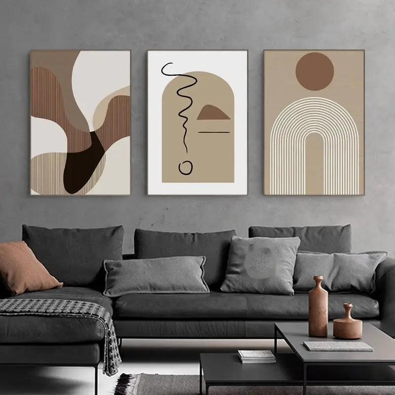 Drei minimalistische abstrakte Wandkunst-Canvas-Druckbilder mit erdigen Farbtönen und geometrischen Motiven, die über einem modernen grauen Sofa angebracht sind.