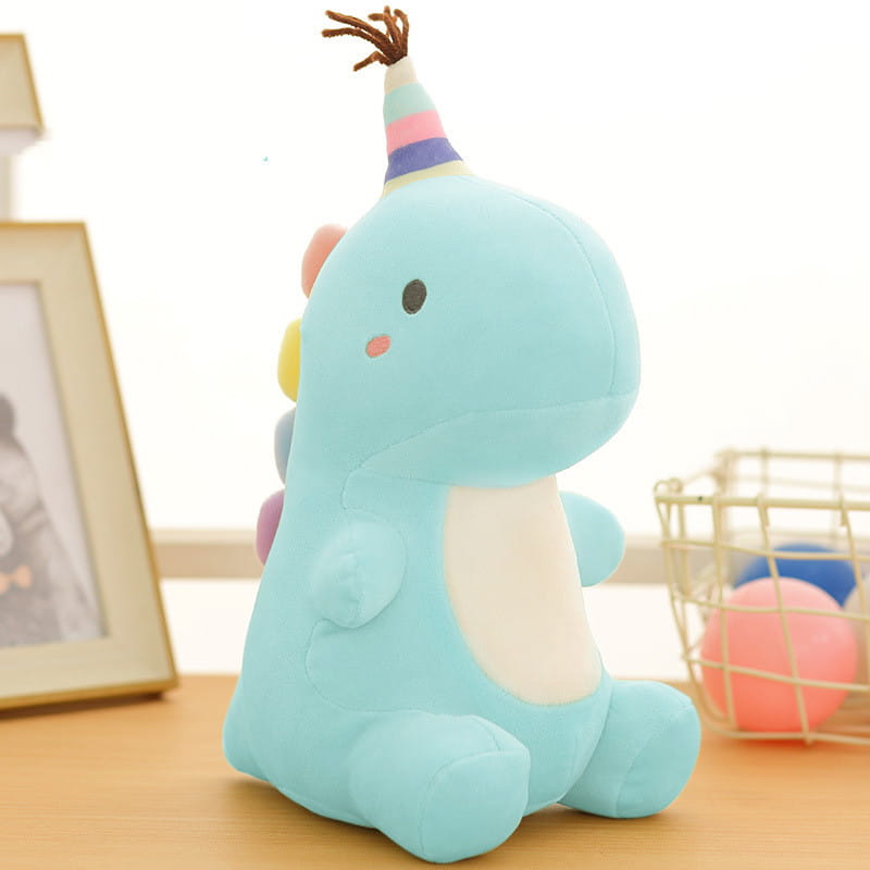 Ein weiches hellblaues Dinosaurier-Plüschtier aus Kuscheltiermaterial mit einer farbenfrohen gestreiften Party-Kappe mit braunen Borsten.
