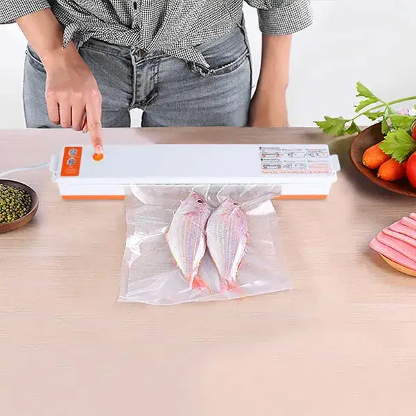 Machine automatique d’emballage sous vide pour aliments blanc et orange, scellant deux poissons entiers dans un sachet en plastique transparent, avec 10 sachets inclus.