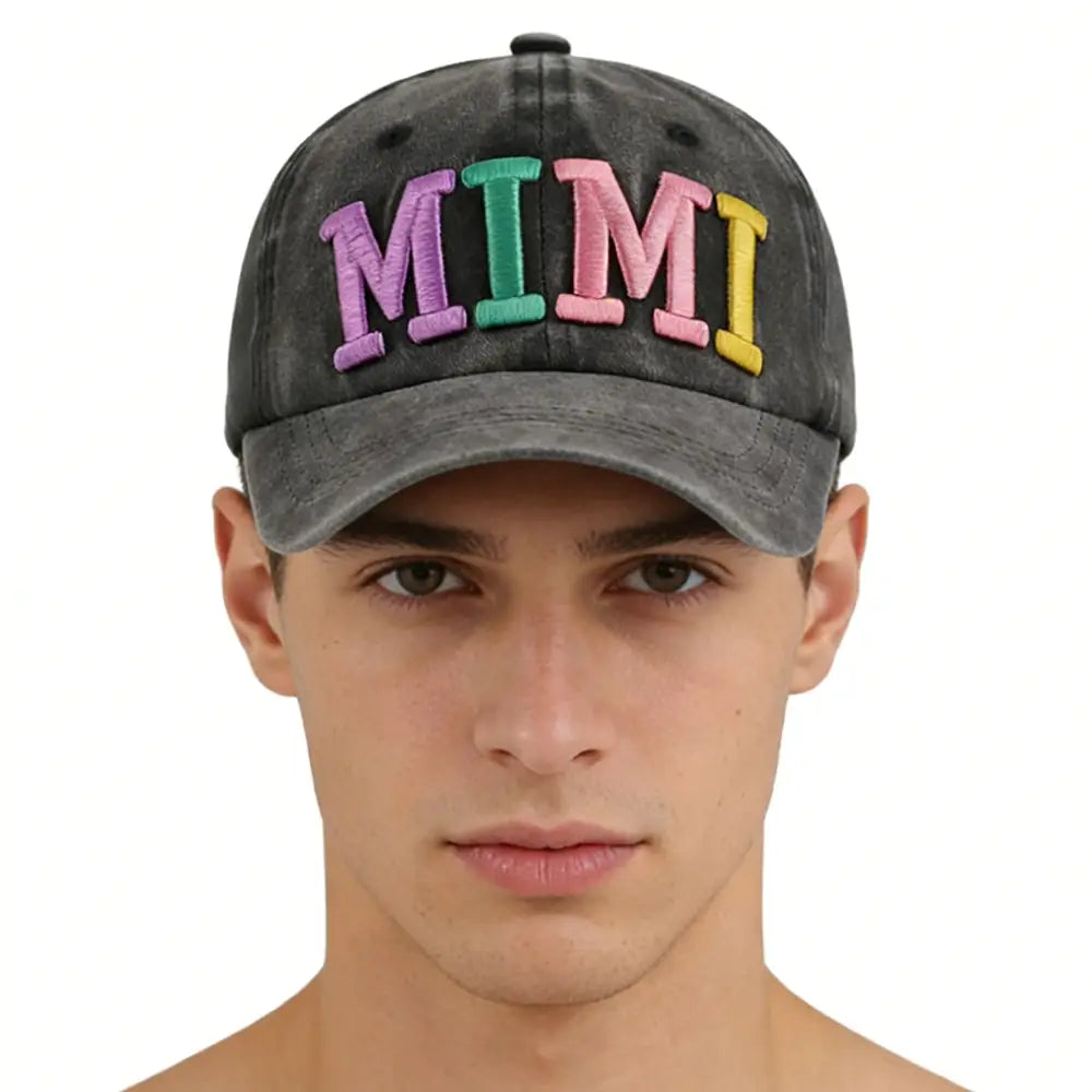 A faded black baseball cap made of cotton features the word mimi embroidered in colorful rainbow-striped letters across the front.