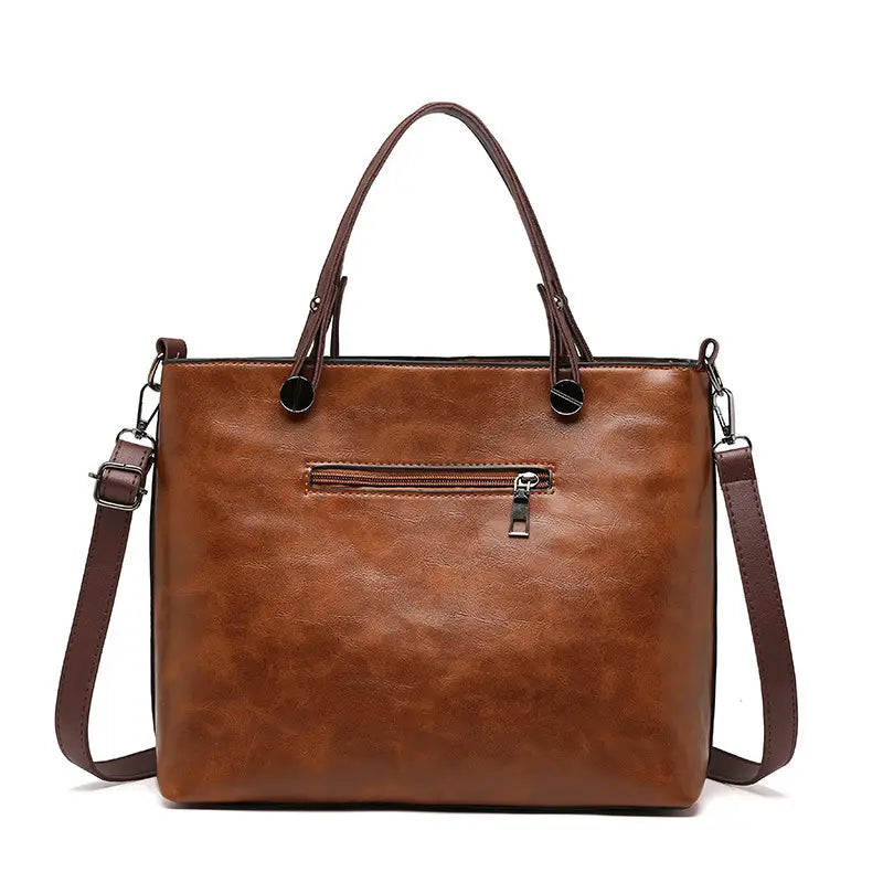 Brown leather tote bag with top handles and detachable shoulder strap designed for large capacity and crossbody use.